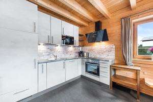 a kitchen with white cabinets and a window at Alpen Chalets Ausseerland - Sauna & BBQ in Bad Mitterndorf