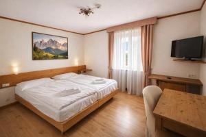a bedroom with a bed and a table and a television at Parc Hotel Victoria in Cortina dʼAmpezzo