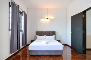 a bedroom with a white bed with a wooden headboard at Gathering Double Storey House-10pax in Kampong Pantai Batu Hitam