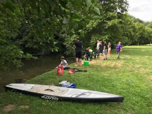a group of people standing in the grass next to a surfboard at ZEcamping 3 étoiles pet friendly en bord de rivière avec une plage de sable in Jumilhac-le-Grand