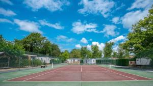 a tennis court with a bench on top of it at ZEcamping 5 étoiles avec piscine chauffée dog friendly sauna tennis 3km plage in Vieux-Boucau-les-Bains