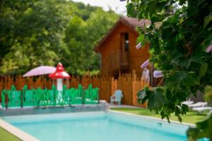 a swimming pool with green chairs and a red umbrella at ZEcamping 4 pet friendly club enfant piscine bar et restanrant in La Bastide-de-Sérou