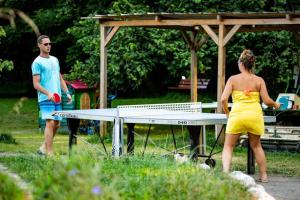 a man and a woman standing around a ping pong table at ZEcamping 4 pet friendly club enfant piscine bar et restanrant in La Bastide-de-Sérou