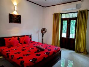 a bedroom with a red bed with red pillows and a window at Villa Keturah in Katunayaka