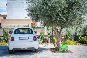 a small white car parked next to a tree at Casale della Vittoria - Guest House in Taranto +28 photos