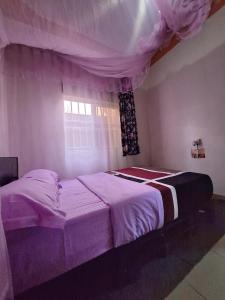 a bedroom with a purple bed with a window at Homey Stay in Kampala