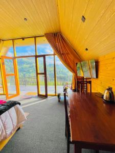 a bedroom with a wooden table in a room with windows at Paddy Breeze Cabana Ella in Ella +55 photos