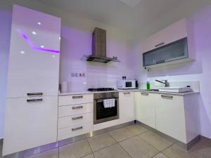 a kitchen with white cabinets and a tv on the wall at Wedgewood - The XL Suite in Sliema