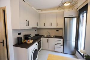 a kitchen with white cabinets and a stainless steel refrigerator at RiposoRooms in Nafpaktos