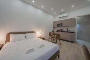 a bedroom with a large white bed and a kitchen at Urban Vibe 1 in Kirkop
