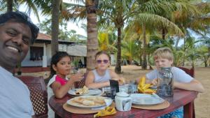 a group of people sitting at a table eating food at Pasikuda Shalom Beach Villa in Kalkudah