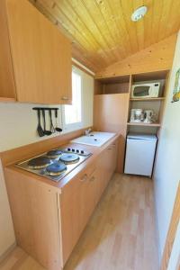 a small kitchen with a stove and a refrigerator at ZEcamping 4 étoiles avec restaurant et animations Alpe dHuez in Le Bourg-dʼOisans