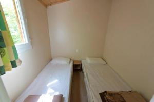 two beds in a small room with a window at ZEcamping 4 étoiles avec restaurant et animations Alpe dHuez in Le Bourg-dʼOisans