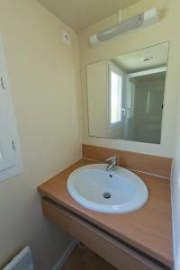 a bathroom with a white sink and a mirror at ZEcamping 4 étoiles avec restaurant et animations Alpe dHuez in Le Bourg-dʼOisans