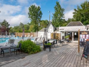 a deck with tables and chairs next to a pool at Camping les 3 Sablières in Saint-Firmin