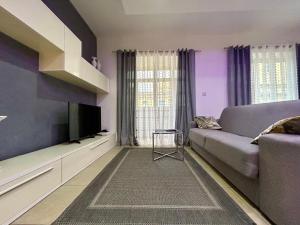 a purple living room with a couch and a tv at Wedgewood - The XL Suite in Sliema
