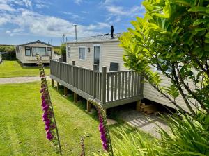a white house with a porch and a person on the roof at Roselands caravan park, Nr Lands End, Cornwall in St. Just