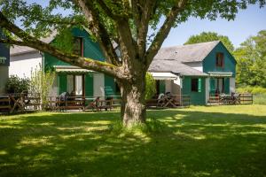 a green house with a tree in the yard at CAMPING LE SAILLET Lestelle Betharram in Lestelle-Bétharram