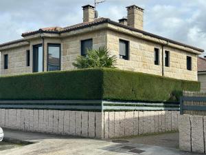 a brick house with a hedge in front of it at La Villa Allariz in Allariz