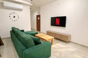 a living room with a green couch and a tv at Large 3-Bedroom with Jacuzzi near St Julians in Is-Swieqi