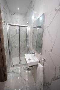 a white bathroom with a sink and a shower at Large 3-Bedroom with Jacuzzi near St Julians in Is-Swieqi +16 photos