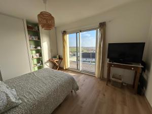 a bedroom with a bed and a television and a window at Les Sternes in Telgruc-sur-Mer