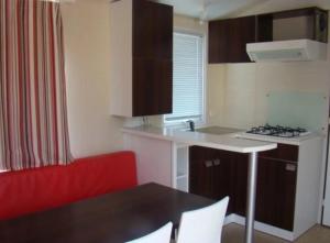 a small kitchen with a table and a red couch at ZEcamping 4 étoiles avec chiens acceptés piscine chauffée à 1km de la plage in Torreilles