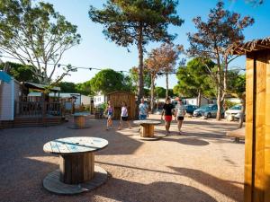 a group of people walking around a park with benches at ZEcamping 4 étoiles avec chiens acceptés piscine chauffée à 1km de la plage in Torreilles