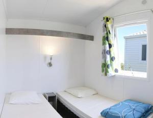 two beds in a room with a window at ZEcamping 3 étoiles piscine chauffée club enfant dog friendly in Ploemeur