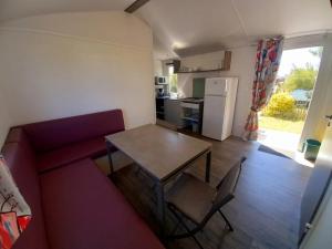 a living room with a red couch and a table at ZEcamping 3 étoiles piscine chauffée club enfant dog friendly in Ploemeur +17 photos