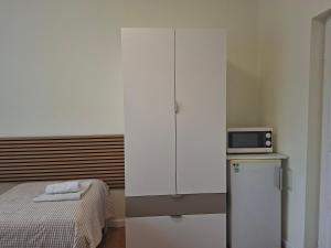 a bedroom with a bed and a white cabinet with a microwave at Emma Apartman 2 in Vecsés