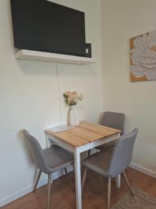 a dining room table with chairs and a vase with flowers at Emma Apartman 2 in Vecsés