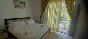 a bedroom with a bed and a window with a balcony at Hotel Gezimi in Shëngjin