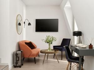 a living room with two chairs and a desk and a tv at Bob W London Hyde Park in London +32 photos