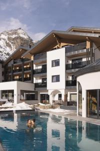 a hotel with a swimming pool in front of a building at Verwöhnhotel Wildspitze in Sankt Leonhard im Pitztal