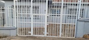 a white gate in front of a building at Spacious one bedroom Bangalow -8E3 in Kampala