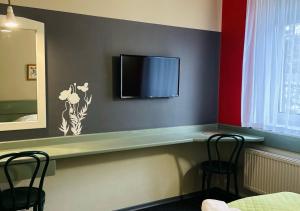 a room with a counter with a tv and two chairs at Hotel Flora in Łódź