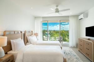 two beds in a hotel room with a window at Ellipse Resort, Grace Bay in Providenciales