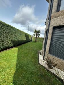 a hedge next to a building with a green yard at La Villa Allariz in Allariz