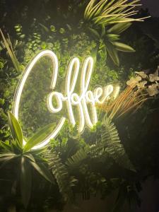 a neon sign in the middle of some plants at Jardin eden88 in Saint Die
