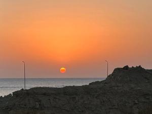 a sunset over the ocean with two street lights at Sea-View 1BR Apartment Balcony Full Kitchen Resort in Marsa Alam City