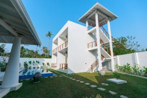 a white house with a swimming pool and a yard at KIRI's HEAVEN in Ahangama