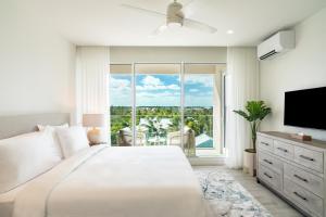 a white bedroom with a large bed and a large window at Ellipse Resort, Grace Bay in Providenciales