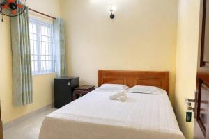 a bedroom with a bed with a white sheets and a window at Tâm Quỳnh Motel in Vung Tau