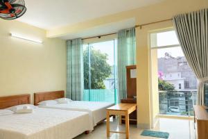 a bedroom with two beds and a large window at Tâm Quỳnh Motel in Vung Tau