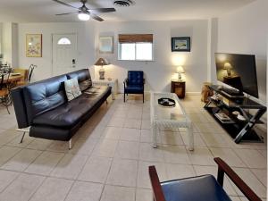 a living room with a black leather couch and a table at Paradise Retreat in Port Aransas