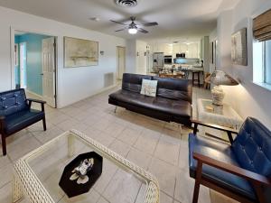 a living room with a black leather couch and chairs at Paradise Retreat in Port Aransas