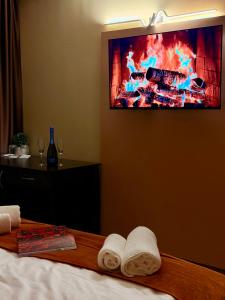 Ein Zimmer mit einem Bett, Handtüchern und einem Fernseher an der Wand. in der Unterkunft Hotel NIRÁ in Sofia
