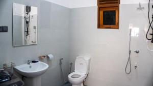 a white bathroom with a toilet and a sink at Golden Breeze Mirissa in Kamburugamuwa