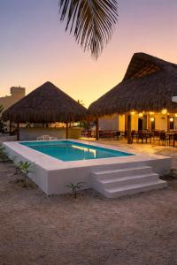 ein Schwimmbad mit zwei Hütten und einem Ferienresort in der Unterkunft Oneiro Suites with Sea View in Mahahual